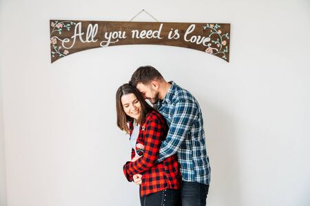 Love story. Young couple in love cuddling under the sign all you need is love