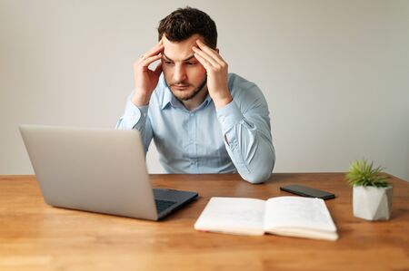 Brainstorm. An office worker in a formal shirt is carefully thinking, he is touching his temples with his fingers. A man solves difficult tasks or issuesの写真素材