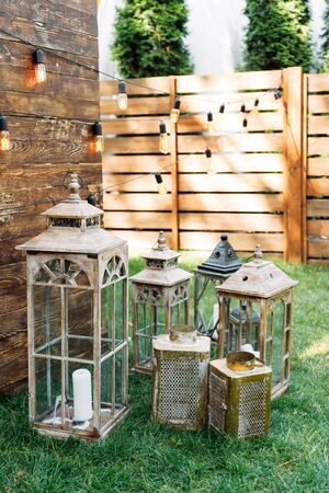 Outdoor wedding ceremony. Oldfashion wooden lanterns in rustic style on the grassの写真素材