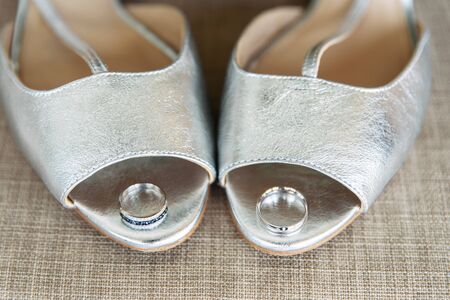 Accessories of the bride. White gold wedding rings on silver bridal shoes. Closeup pictureの写真素材