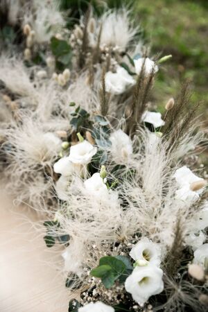 Outdoor summer wedding in rustic style, pine forest around. Wedding arch of fluffy spikelets, dried flowers and eustoma flowers, candles on the floor. Close up pictureの写真素材