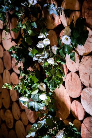 Wedding decor. Flowers and green branches on a wooden wallの写真素材