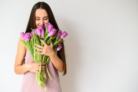 Close up portrait of a young beautiful girl with a bouquet of flowers, in bloom. Bright spring colors. Horizontal picture on white backgroundの写真素材