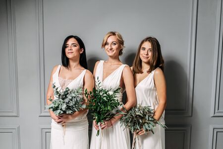 Wedding day. Three different girls in wedding dresses with bouquets in their hands. They are laughing. close-up portraitの写真素材