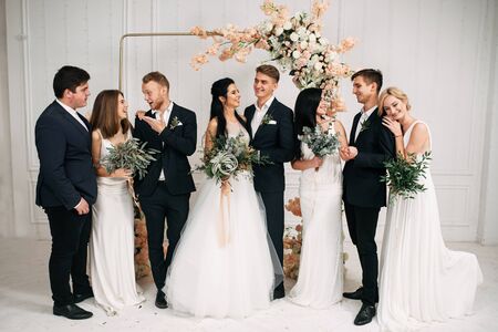 Wedding day. A newlyweds, bridesmaids in white dresses and best men in suits communicate freely near the archの写真素材