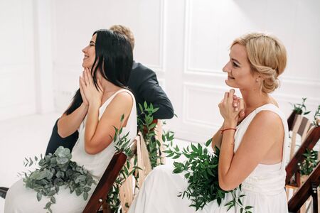 Indoor boho style wedding ceremony. The exited guests look at the newlyweds with tears of joy in their eyesの写真素材