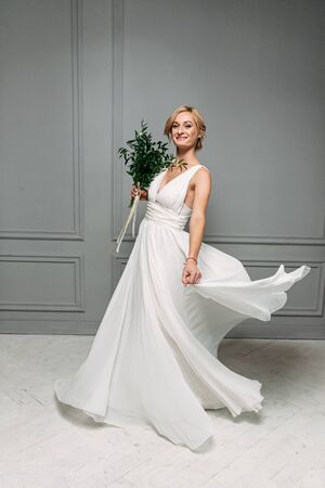 Happy bride. Slender blonde is spinning in a long dress. Photo in motion indoorsの写真素材