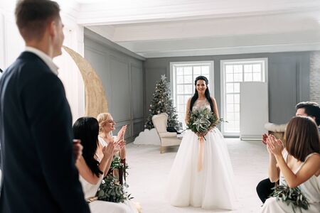 There is a bride. A beautiful young bride in a chic dress goes to the altar, the groom looks at herの写真素材
