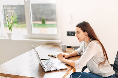 An office employee works from home. Video call meeting, online conference. A young guy sits in front of a laptop and talkingの写真素材