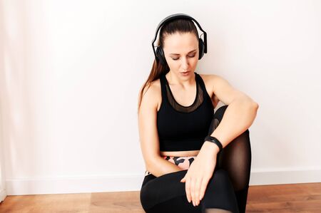 Beautiful athletic woman in headphones tired, break between workout sets. Healthy lifestyle concept. Close-up portraitの写真素材