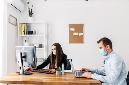 Office work during the epidemic of coronavirus, seasonal flu. Employees at the table in medical masks.の写真素材