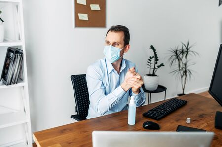Treat your hands with an antiseptic. A man in an office in a medical mask treats his hands with a disinfectant to combat viral diseases, coronavirusの写真素材