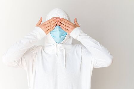 Fear of a pandemic, coronavirus epidemic, covid. A woman in a protective suit and medical mask closed her eyes with her hands.の写真素材