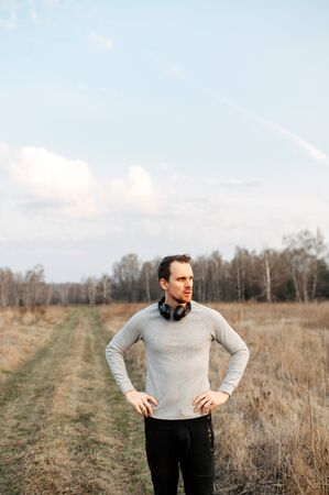 A beginner guy in sports. Young attractive athletic guy getting ready for a run in the country. He stands inspired with his hands on his hips.の写真素材