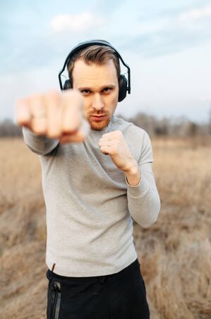 Get in shape. A young guy in headphones is doing sports training in the open air in the spring. He...