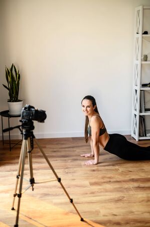 Young sporty slim woman yoga coach records video online training hatha yoga. Healthy lifestyle concept, video tutorial conceptの写真素材