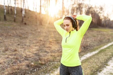 Young attractive woman ties her hair in a bun before doing sports, she is going to run outdoors. Sport lifestyleの写真素材