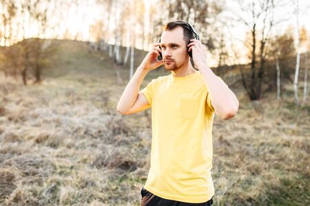 Sports with a favorite soundtracks. Attractive guy with headphones listens music and going to do outdoors workoutの写真素材