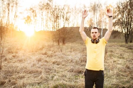 Training outdoors. Young attractive athletic man doing exercises in the countryside. The concept of self-discipline and a healthy lifestyleの写真素材