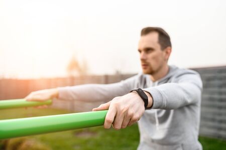 Athletic young man is going to do exercises on parallel bars outdoors. Healthy lifestyle concept