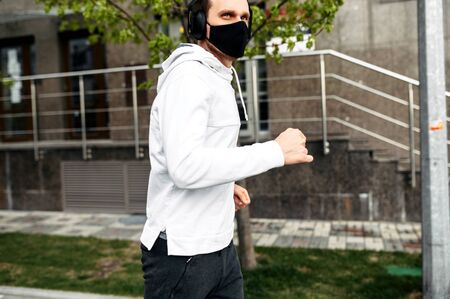 Keep in shape during quarantine. A young man in sports clothing is running in the city outsideの写真素材