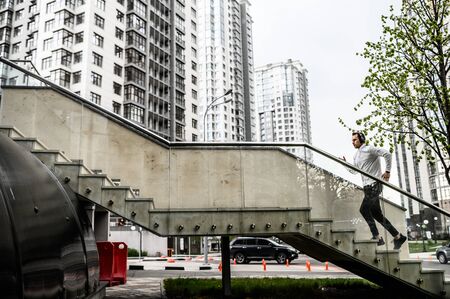 Healthy habits. Full length of young man in sports clothing is running up stairs while exercising outsideの写真素材