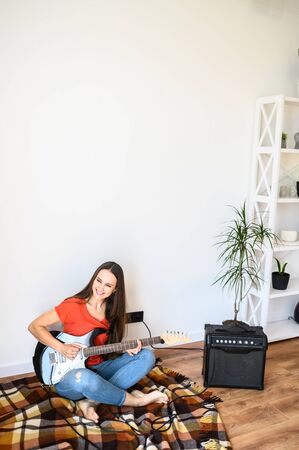 A girl spends home leisure playing an electric guitar. Hobby concept, talentの写真素材
