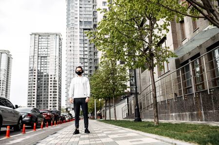 Full length of young man in sports clothing with headphones going to run among urban landscapeの写真素材