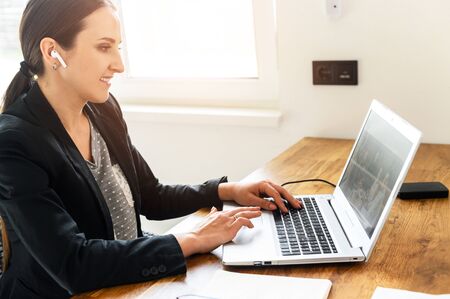 Home office. A young woman uses laptop for video call, he sits at the kitchen table and looks in webcamの写真素材