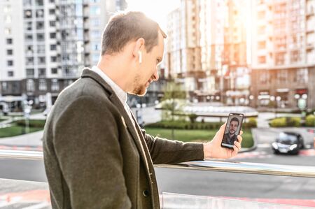 Communication via video call. Two men have distance business meeting by the phone outdoorsの写真素材