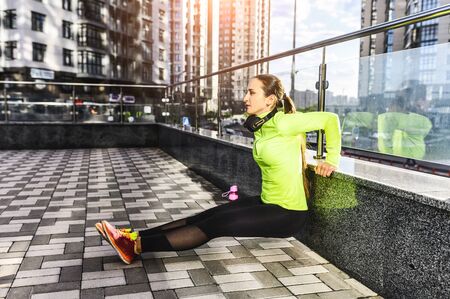 Street full body workout. Athlete woman in sportswear is doing bodyweight tricep exercises outdoors. Healthy lifestyleの写真素材