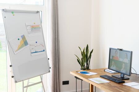 Empty office for video conference. A flip chart with graphs and diagrams in front of pc screen with online audienceの写真素材
