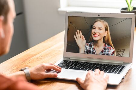 Back view of man making video call with his female friend or coworker while staying at home. Zoom, video communicationの写真素材