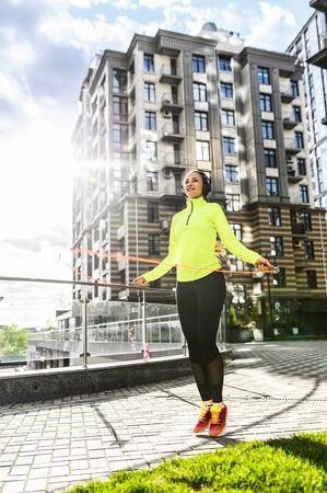 Lose weights workout. A young woman is jumping rope outdoors among high-rising building. Healthy lifestyle conceptの写真素材