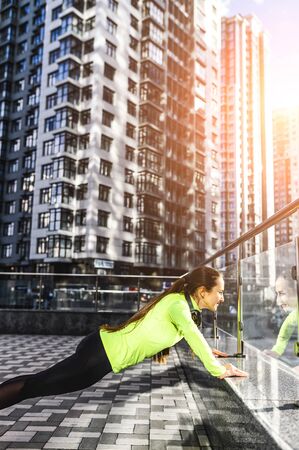 Street workout. Athlete woman in sportswear is doing push-ups outdoors.の写真素材