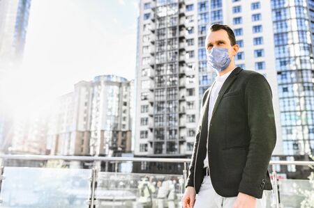 A guy in smart casual wear with a surgery protective mask on the face in the downtown. Stay safety during quarantine, epidemiaの写真素材