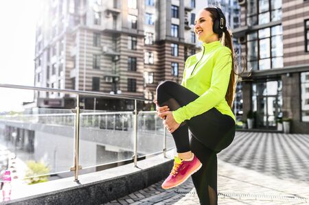 A young woman in sportswear is doing stretching exercises outdoors, she is warming up before workout. Healthy lifestyle conceptの写真素材