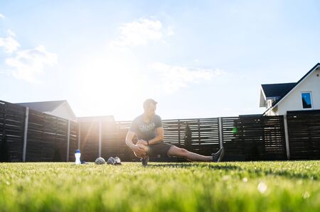 Stretching exercises before outdoors training. A guy is warming up on the lawn in the backyardの写真素材