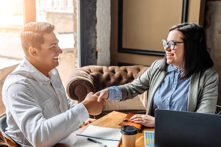 You are hired. A girl recruiter shakes hands with a man as a sign of acceptance for a new position. The man is happyの写真素材