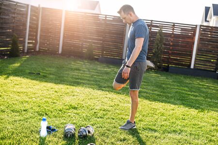 Young athletic guy is doing sports training outdoors in the backyard. He warm up before load. Self-discipline and a healthy lifestyle conceptの写真素材