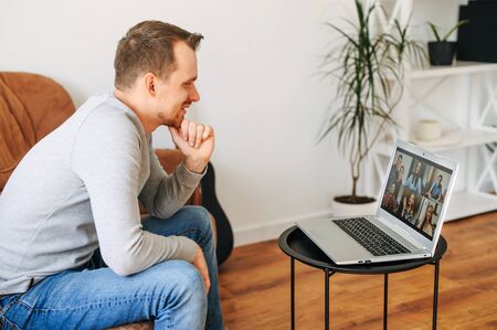 Video call with a group of people. A guy is using laptop for talking online with a several people togetherの写真素材