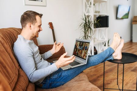 Video call with a group of people. A guy is using laptop for talking online with a several people togetherの写真素材