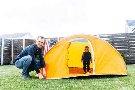 Young father and little cute son enjoy spend time together. Dad and son play in tent in the backyardの写真素材