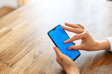 Female fingers is zooming something on smartphone screen. A phone with blank screen for inserting textの写真素材