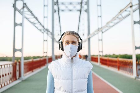 Healthy active lifestyle during pandemic. Portrait of young fitness women with a medical mask on a...