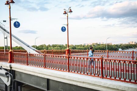 Back view of running girl on the pedestrian bridge. Morning jogging in the city. Healthy lifestyle conceptの写真素材