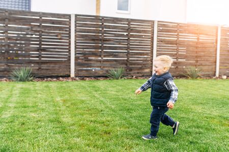 Cute baby boy is running on the green grass and laughs. Happy childhood in the countrysideの写真素材