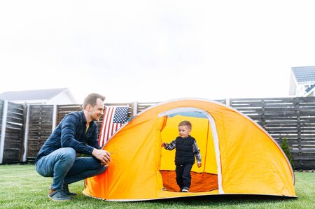 Father and son have wonderful day together. Young father and his cute toddler boy camped in the backyard, they are playing in a tentの写真素材