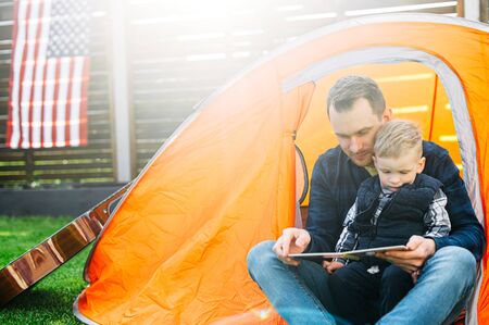 Dad and son set up tent in the backyard and spend time together playing in it. Family time outdoorsの写真素材