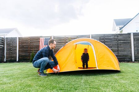 Young father and little cute son enjoy spend time together. Dad and son play in tent in the backyardの写真素材